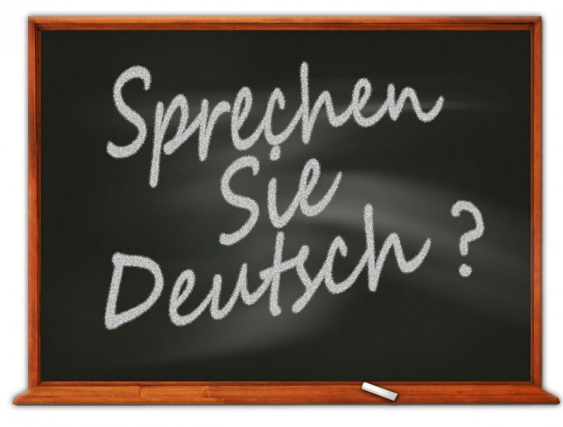 Na czarnej tablicy widnieje napisany białą kredą tytuł zajęć: Sprechen Sie Deutsch?