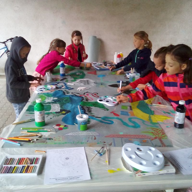 Dzieci malują przy wspólnym stole, jedną pracę.
