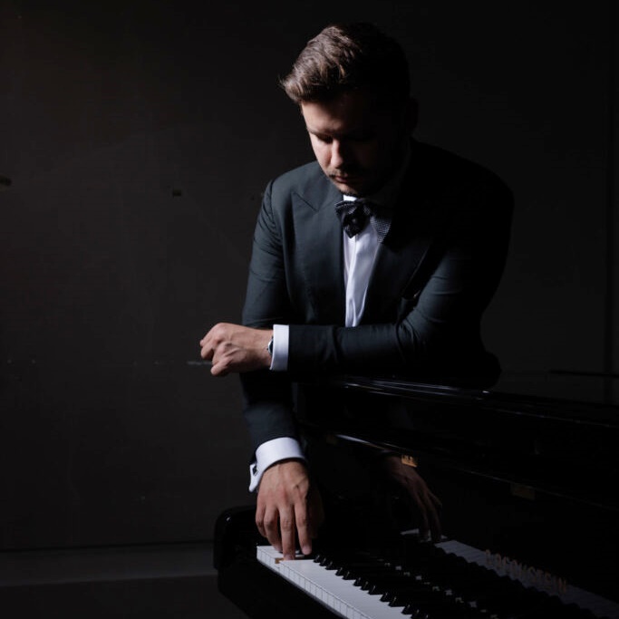 Elegancki mężczyzna dotyka klawiatury fortepianu